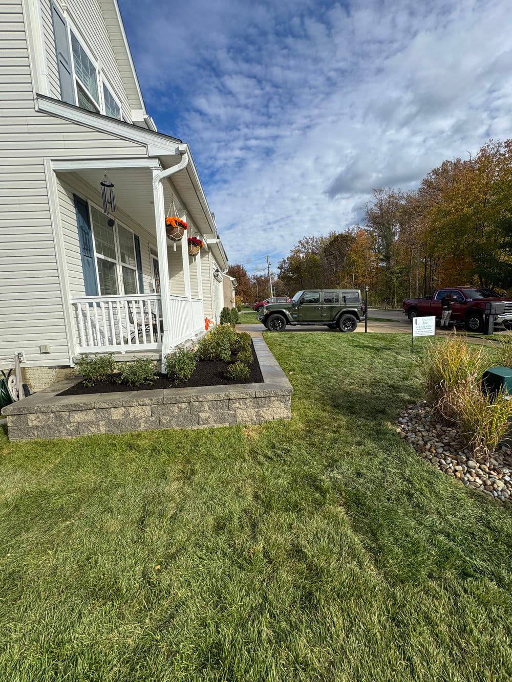 Home exterior with landscaping and a gray Jeep parked in a driveway on a sunny day.
