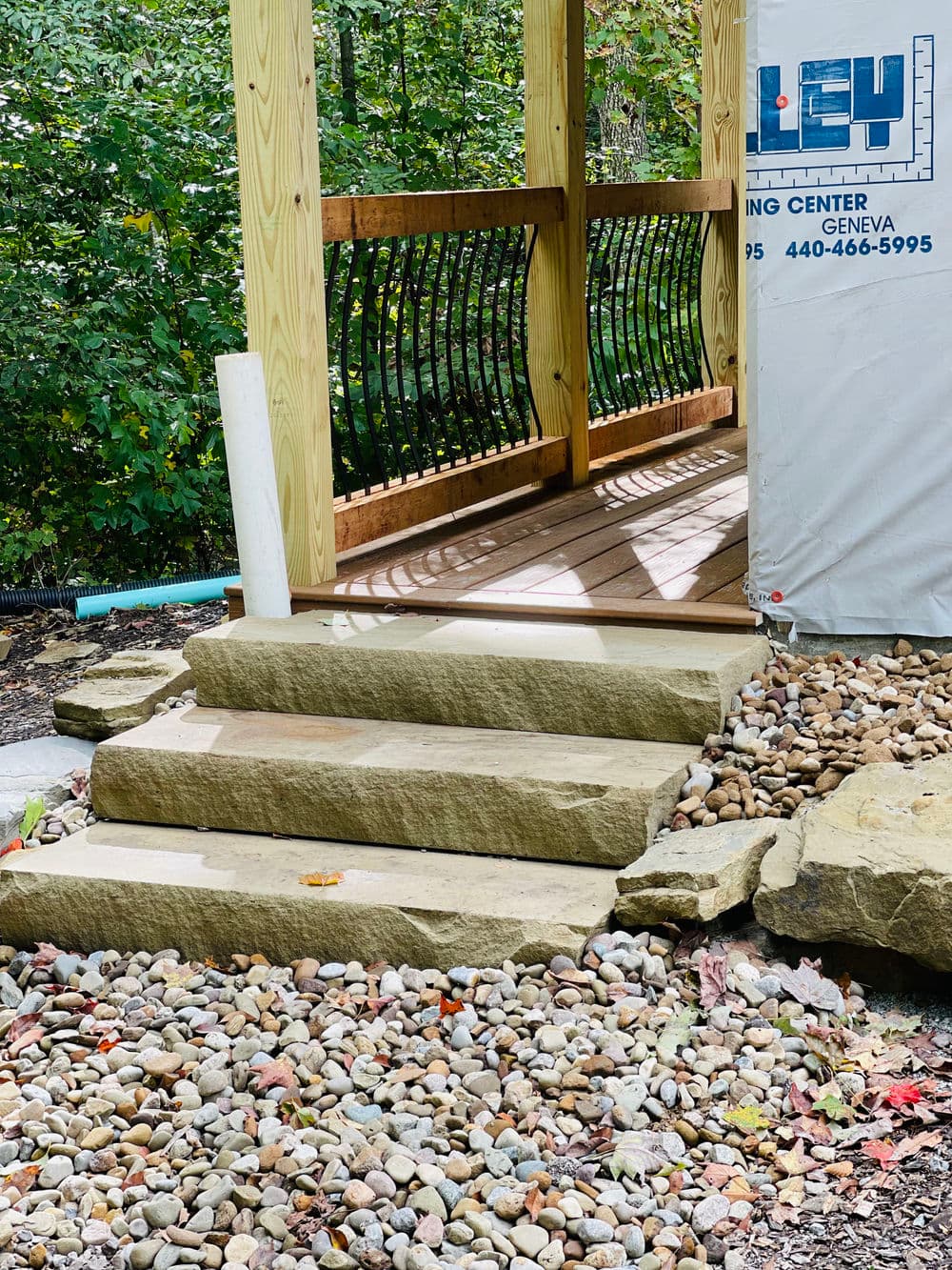 Stone steps leading to a wooden gazebo with a landscaped pebble area.