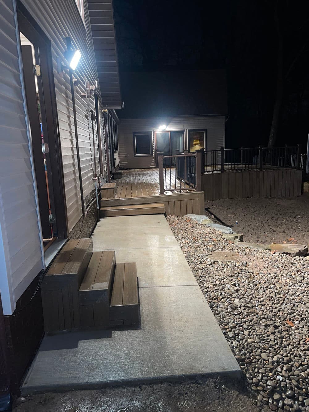 Well-lit pathway leading to a house at night, featuring steps and gravel landscaping.