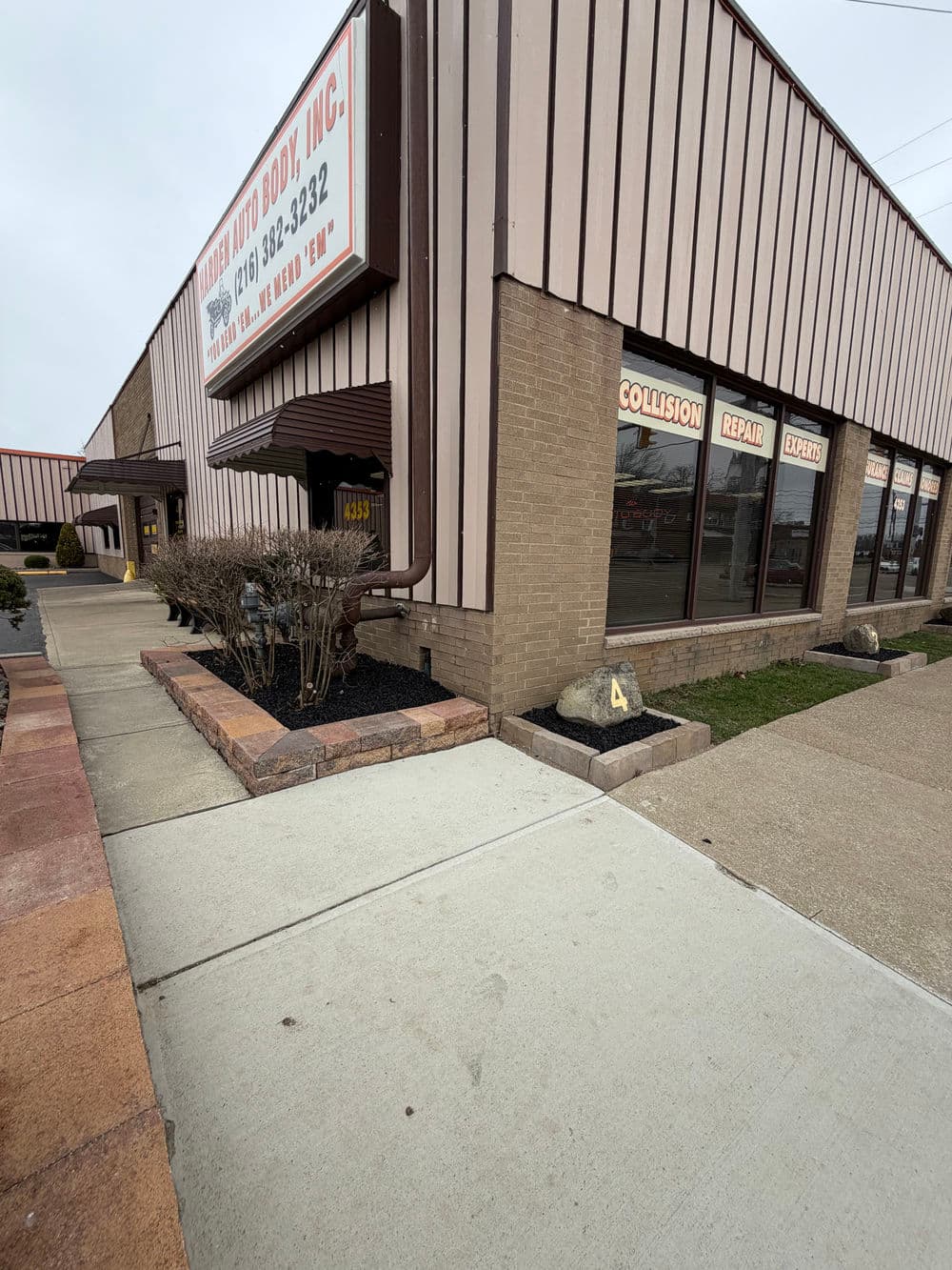 Auto body shop exterior with signage and clean walkway, showcasing collision repair services.