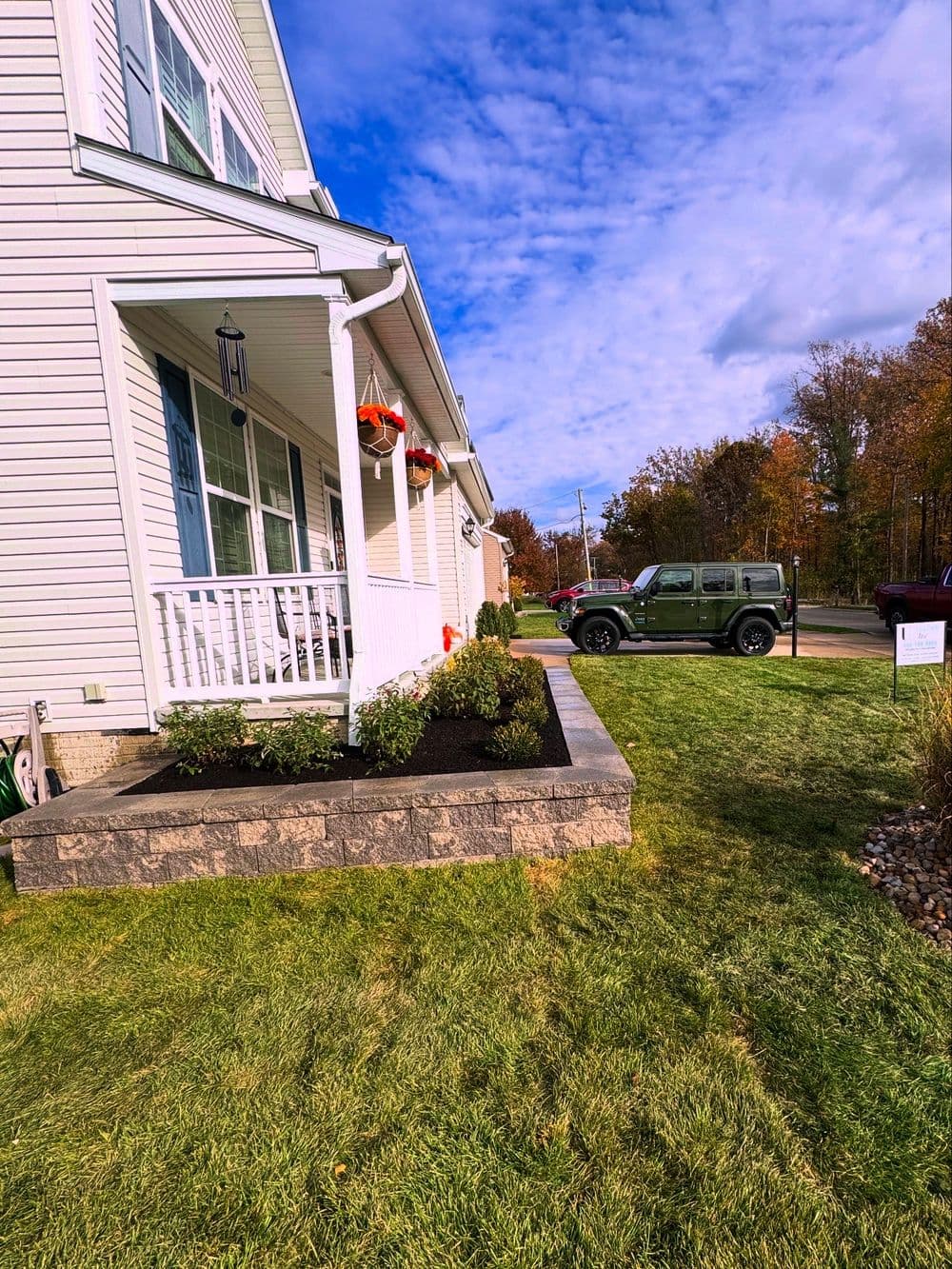 House exterior with landscaping, parked Jeep, and autumn foliage in the background.
