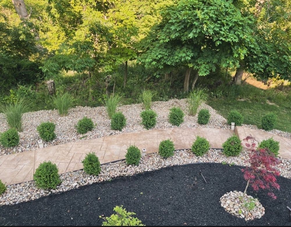 Lush landscape design featuring stone pathway, green shrubs, and decorative gravel garden.