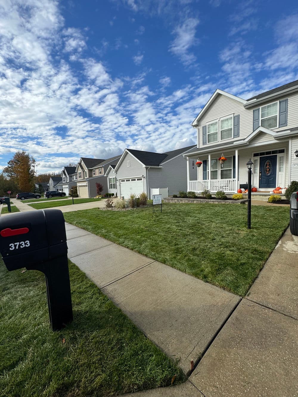 Front view of a suburban house with autumn decorations and a mailbox on the lawn.